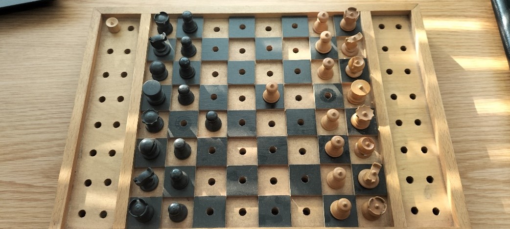 A Braille Chess board, all the black tiles are raised and each black piece has a raised dot on it's top.