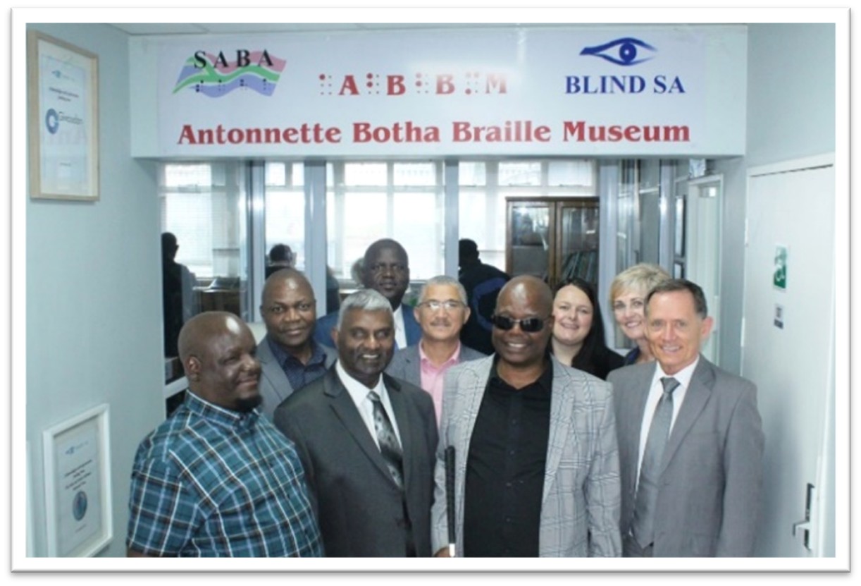 The ABBM board and partners at posing in front of the ABBM musueam entrance, with the Blind SA and SABA logo on either side of ABBM.